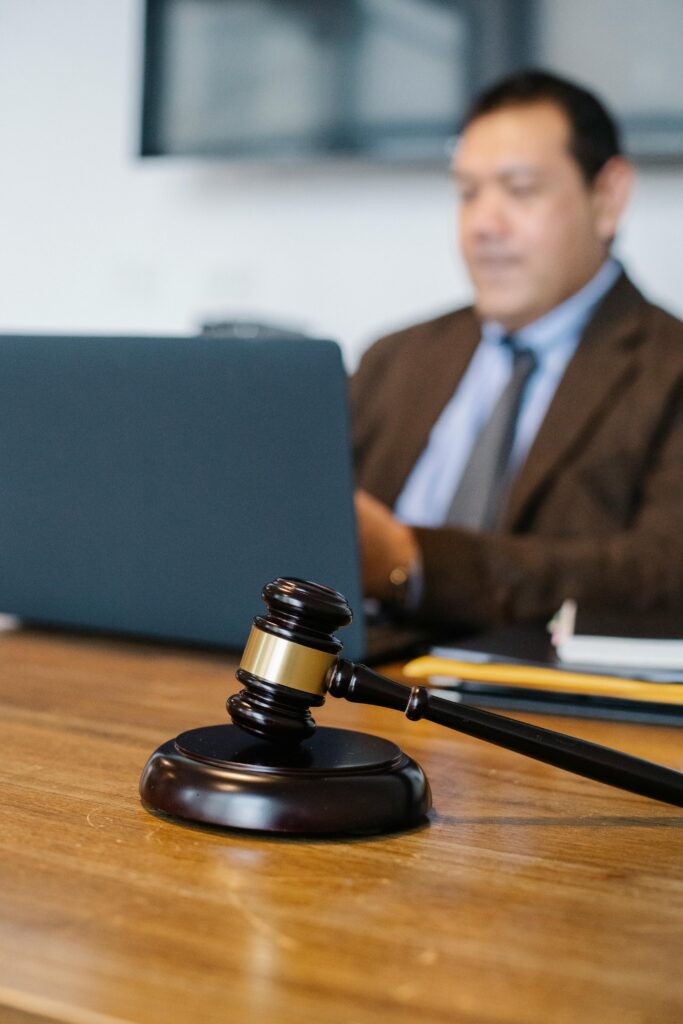 Desk with a black and gold gavel with blurred image of man in suit